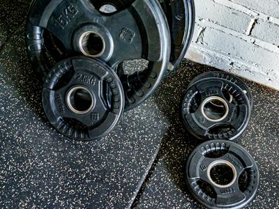 Close up of a metal barbell with black weight plates.