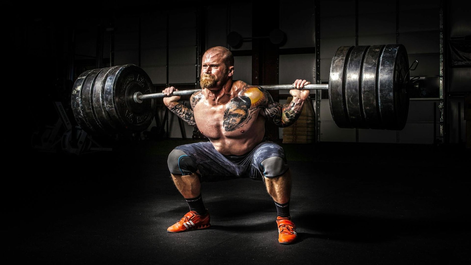Strong man performing heavy lifting in a dark gym environment.